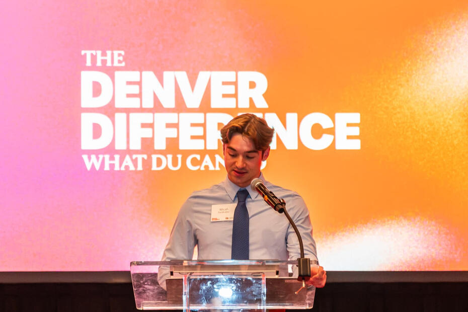 Micah DenBraber speaking at a podium at a University of Denver event.